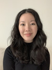 an asian woman in a black sweater sitting on a couch